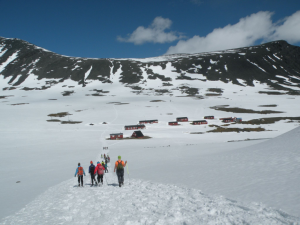 Several groups of snowshoers hiking toward Part of the study abroad in Sweden took place here at Tarfala Research Station with mountains in the background.